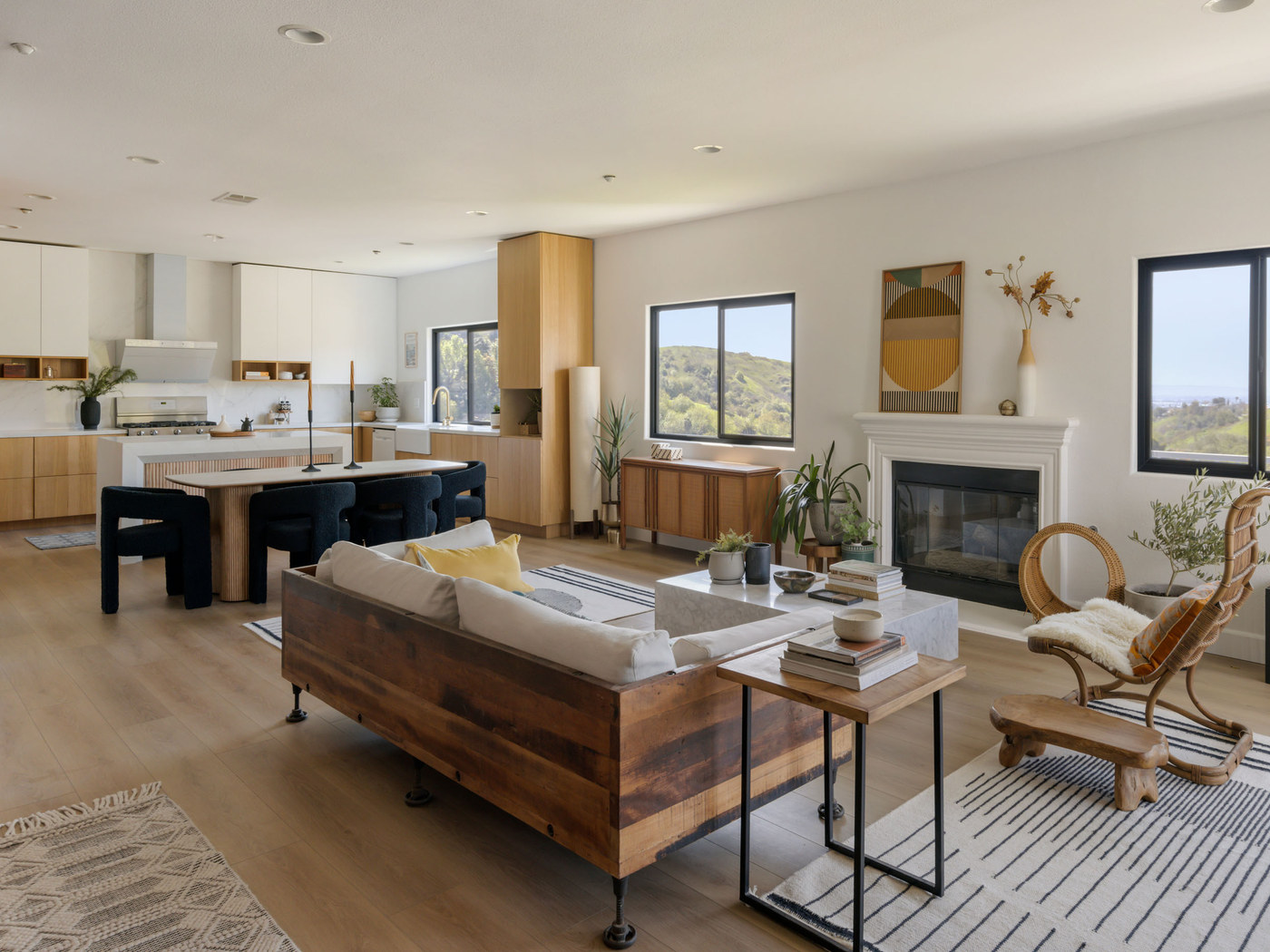 A warmly lit California kitchen and living room with hillside views.